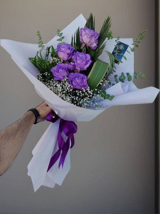 **"دسته گل رز بنفش ۵ شاخه با برگهای تازه، تزئین شده با گلهای ریز سفید ژپسوفیلا و کاور کادویی بنفش پاستیلی"**